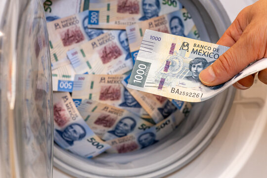Mexico money. close up of hand putting Mexican Peso banknotes into a washing machine. Literal money laundering concept, financial crime, corruption and business background.