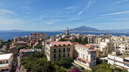 Obraz premium Aerial drone view of Vico Equense town with colorful buildings, church dome and Mount Vesuvius volcano across the Gulf of Naples, Italy 