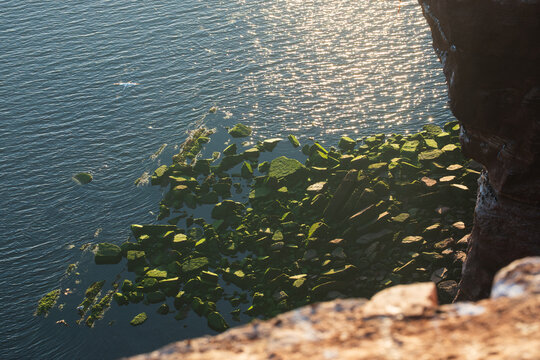 Top Down View of Mossy Green Boulders and Waves Crashing on Shore, The Concept of Coastal Erosion