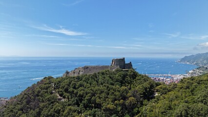 Fototapeta premium Aerial view of Castello di Arechi medieval fortress rising above lush forested hill with vast blue Gulf of Salerno and Amalfi Coast coastline, Italy