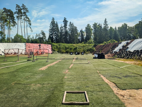 Empty outdoor practical shooting range stage with wooden starting box on green turf grass for action sport competition under summer sky