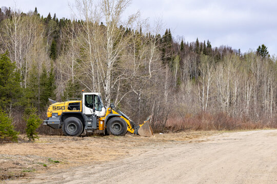 Parents, Quebec, 20 May 2026 : A yellow and white Liebherr  wheel loader stands on a dirt road near a forest.