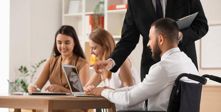 Young man in wheelchair using laptop with human resources commission during job interview at office