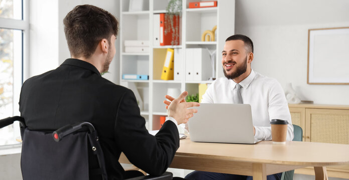 Male human resources manager interviewing job applicant in wheelchair at office