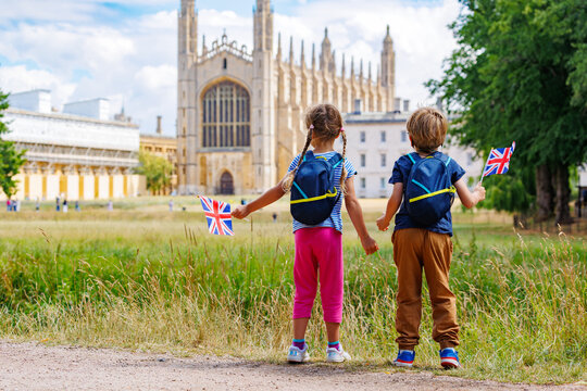 Two children with backpacks waving British flag visit Cambridge