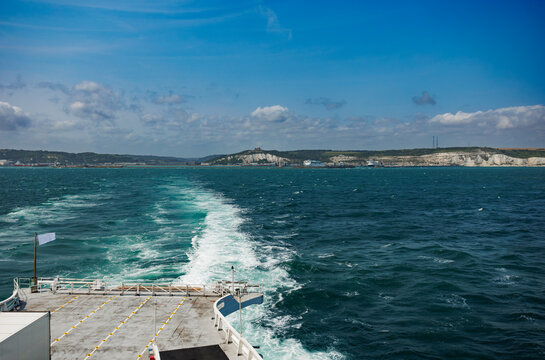 Ferry deck view over blue sea toward distant cliff coast horizon