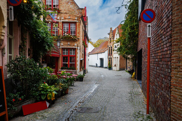 Naklejka premium Cobbled European alleyway street with cafes in Bruges, Belgium