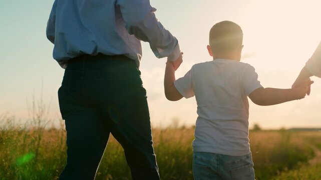 Parents, child son run hand in hand, nature, sun. Father mother, child son playing outdoors. Happy family, papa mama, kid boy, walking in park, summer. Family picnic. Dad kid mom vacation countryside