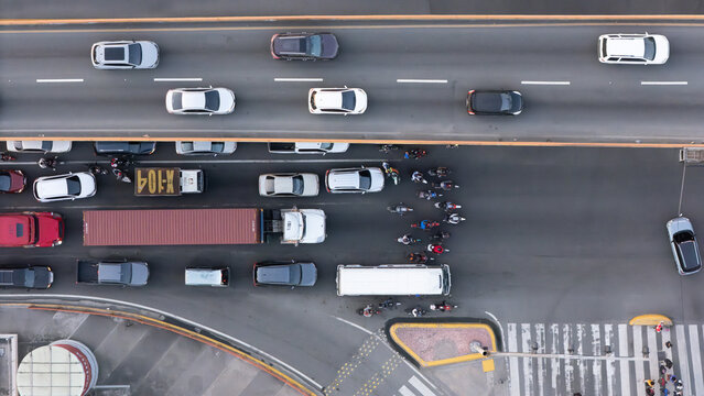 Aerial view of a busy road intersection with cars, trucks, and motorcycles navigating through traffic lanes in the Dominican Republic.