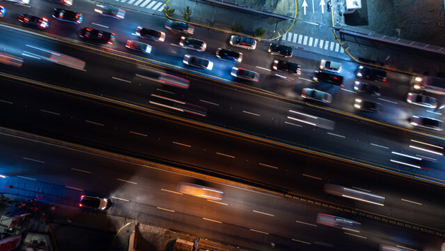 Aerial view of a busy highway at night with light trails from moving vehicles, illuminated road markings, and dark surroundings in the Dominican Republic.