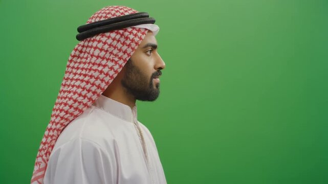 Profile view of a young Middle Eastern man wearing traditional clothing isolated on green screen chroma key background.