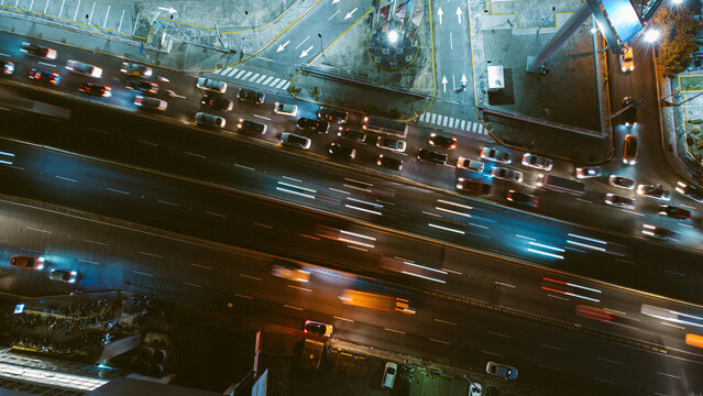Aerial view of a busy highway at night with light trails from moving vehicles, illuminated road markings, and urban infrastructure in the Dominican Republic.