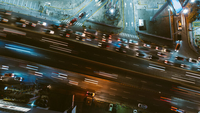 Aerial view of a busy highway at night with light trails from moving vehicles, illuminated road markings, and urban infrastructure in the Dominican Republic.