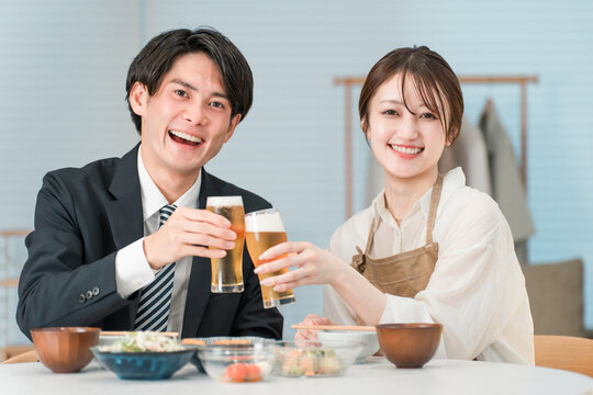マイホームのダイニングテーブルで食事,晩酌をする若いアジア人夫婦,カップル