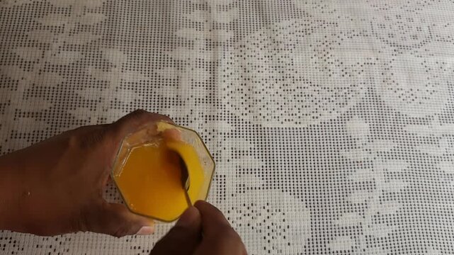 Stirring Turmeric Powder into Fresh Orange Juice with Spoon