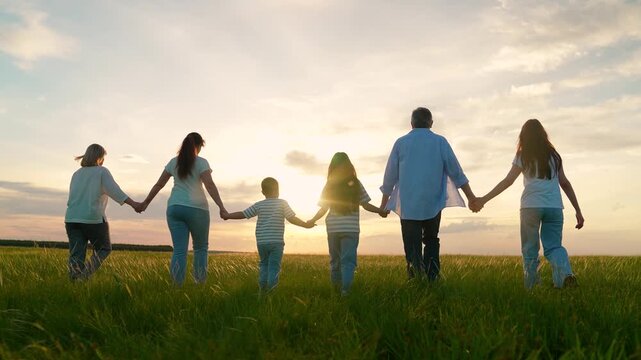 Parents, dad mom children picnic, green lawn. Happy group people, adults children, enjoy walk on green grass. Happy family, children, papa mama son daughter stroll through summer field, holding hands