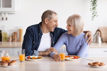 Smiling Elderly Caucasian Man And Woman Having Breakfast Together In Kitchen, Enjoying Healthy Meal...