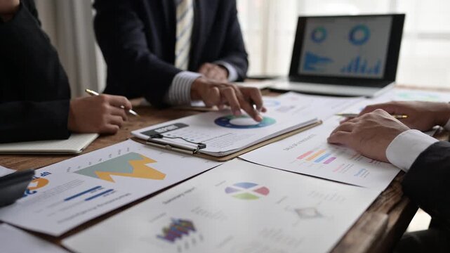 Business people analyzing financial charts and graphs on wooden table