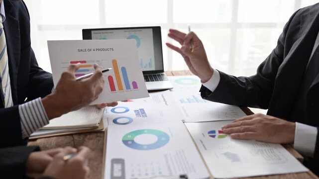 Businessmen discussing sales performance with charts and graphs