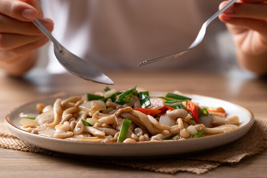Eating stir-fried oyster mushroom with onion, sping onion, chili and soy sauce. Asian vegetarian food