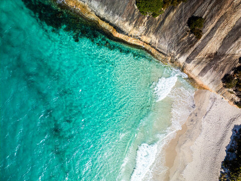 Aerial view of Misery Beach with turquoise water, white sand, and dramatic rocky cliffs in Torndirrup, Western Australia, Australia.
