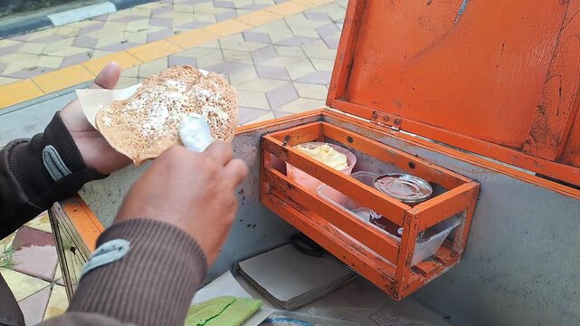 Close-up of an Indonesian street food vendor preparing "Terang Bulan Jadul" (classic thin sweet pancake). The video shows the vendor skillfully spreading chocolate sprinkles (meses) and condensed milk