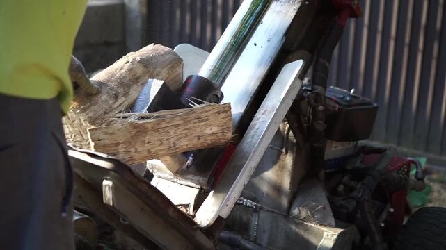 Detailed side-angle shot of a hydraulic log splitter processing firewood, showing the mechanical wedge splitting a large wooden block effortlessly.