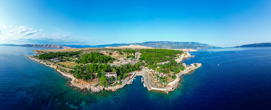 Aerial view of Goli otok, a historic island with abandoned prison buildings, dense pine forests, and rocky coastlines surrounded by the Adriatic Sea in Primorje-Gorski Kotar, Croatia.