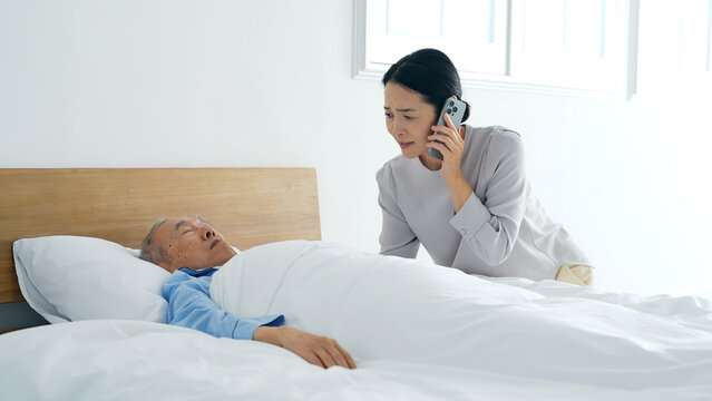 昏睡するシニア男性とスマホで電話する女性