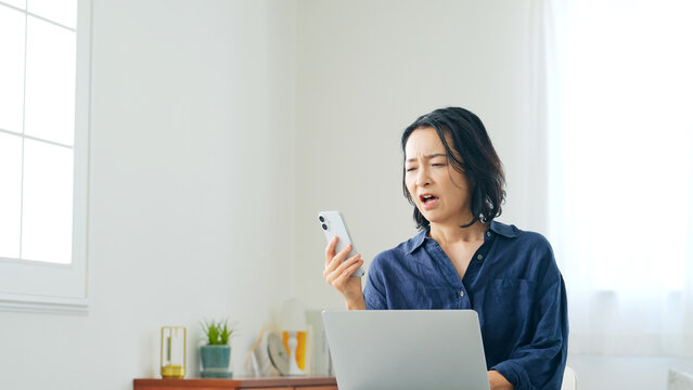 スマホとパソコンを見ながらがっかりする女性