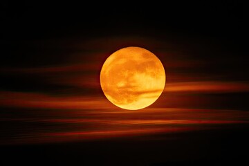 Obraz premium Fiery sun orb glows intensely, partially obscured by streaking red-orange clouds