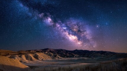 Obraz premium Vibrant Milky Way galaxy stretches across a starlit sky over rugged desert terrain