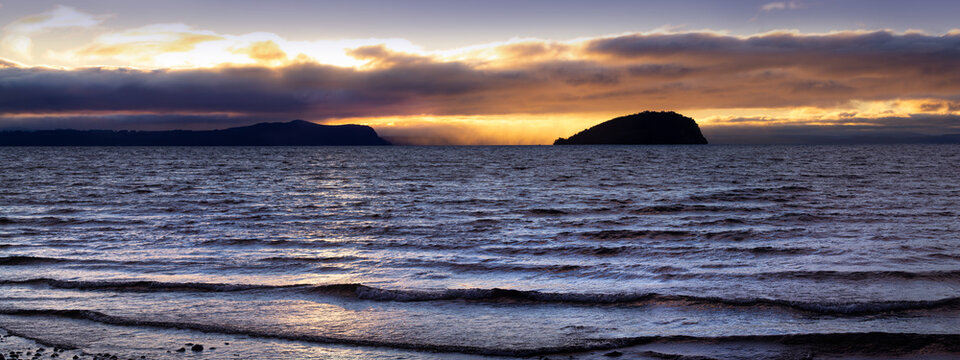 Lake Taupō, New Zealand at sunset, panoramic view from Motutere. Motutaiko Island, highly sacred Māori wāhi tapu and burial ground for the local Ngāti Tūwharetoa iwi.