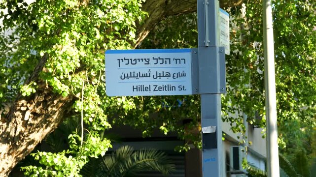 Street sign for Hillel Zeitlin Street in Tel Aviv, Israel surrounded by greenery, establishing shot, urban neighborhood identity and city guides.
