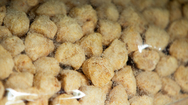 Macro shot of dry soy protein chunks in a clear plastic package. A macro close-up showcasing dry chunks of textured vegetable protein (TVP) or soy protein pieces visible through a clear plastic packag