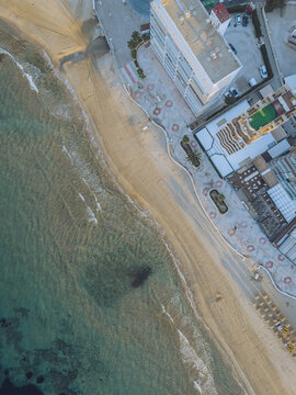 Aerial view of the sandy beach and coastal promenade featuring modern apartment buildings, palm trees, and clear turquoise waters in Calp, Valencian Community, Spain.