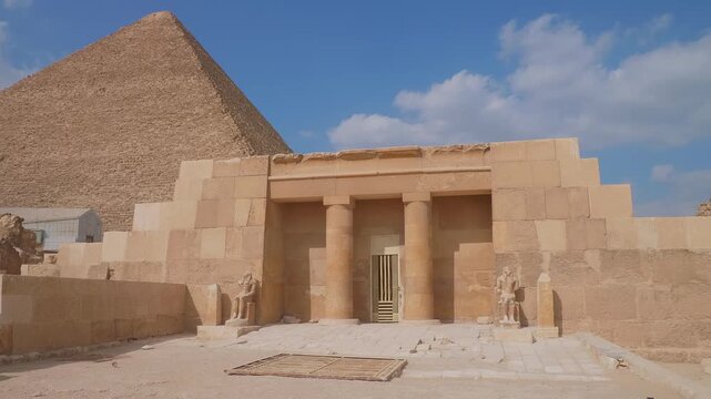 Experience the awe inspiring grandeur of the Great Pyramid of Giza under a clear blue sky, alongside the intricately designed entrance to an ancient Mastaba tomb, likely the Mastaba of Seshemnefer IV,