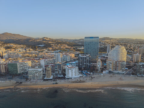 Aerial view of high-rise apartment buildings, hotels, sandy beaches, and the Mediterranean Sea along the coastline in Calp, Valencian Community, Spain.