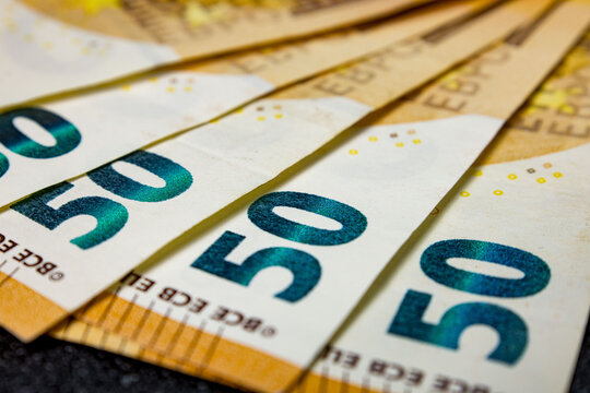 Several fifty euro banknotes arranged in a fanned-out pattern, showcasing the number prominently. The focus is on the texture and security features of the currency notes, highlighting the European Uni