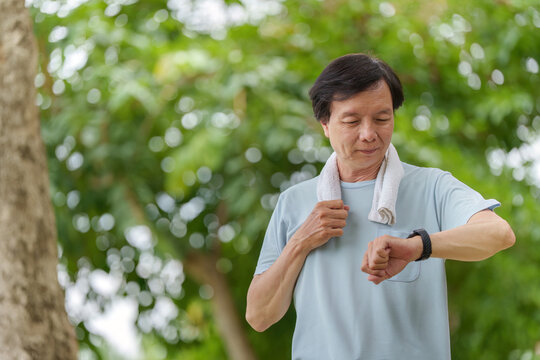 Senior Asian man checking smartwatch after exercise for fitness technology and health monitoring one person
