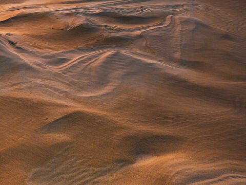 Aerial view of wind-swept sand dunes with intricate patterns and golden hour light at Two Peoples Bay Nature Reserve, Nanarup, Western Australia, Australia.