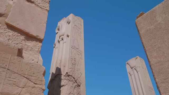 Explore the grandeur of ancient Egypt with this captivating footage showcasing the majestic ruins of a temple complex, featuring a towering obelisk adorned with intricate hieroglyphs and weathered sto