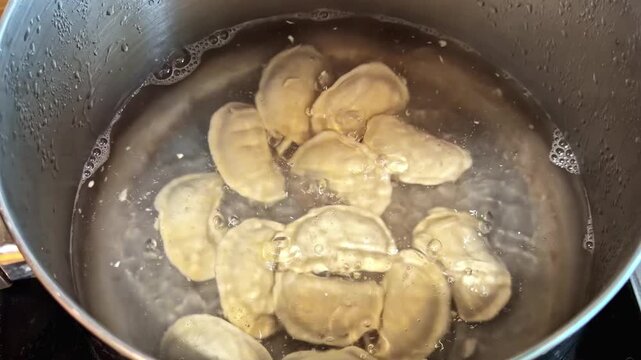 Dumplings or pierogis boiling in pot of water on stovetop during meal preparation