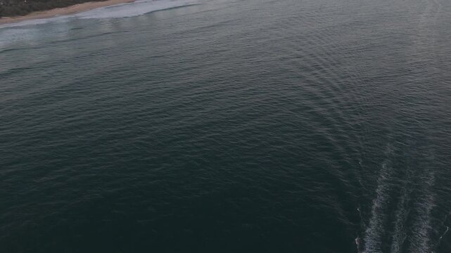 Motorboat Speeding In The Water Leaving A White Foamy Wake With Surfers Paradise Skyline In The Distance At Sunrise In Gold Coast, QLD, Australia. - aerial tilt up shot