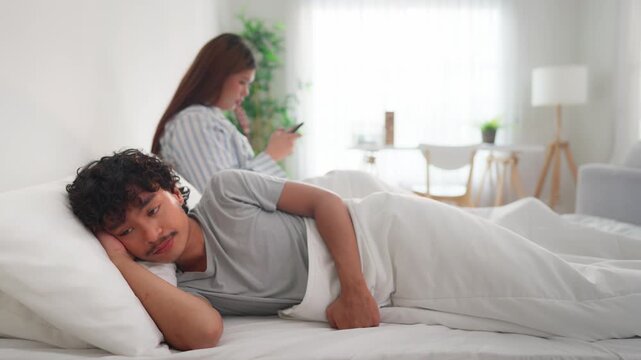Asian LGBTQ couple lying down on bed with painful after fight argument. 