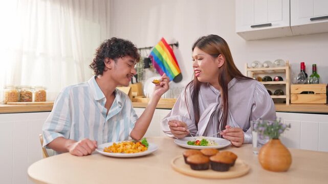 Asian transgender woman and her male partner eating breakfast in house. 