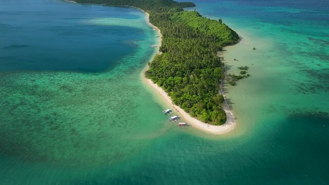 Aerial tilt-up reveals entire stretch of Capsalay Island white sand beach flanked by turquoise reef shallows and deep blue lagoon in San Vicente, Palawan