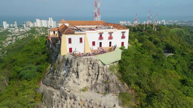 Aerial parallax of white colonial Convento de la Popa monastery on rocky clifftop with Cartagena city panorama and Caribbean sea behind in Colombia