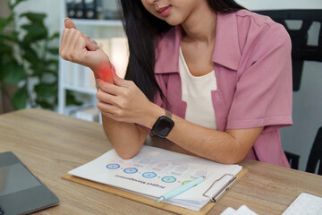 Cropped shot of woman holding painful wrist with red glow over desk for carpal tunnel syndrome