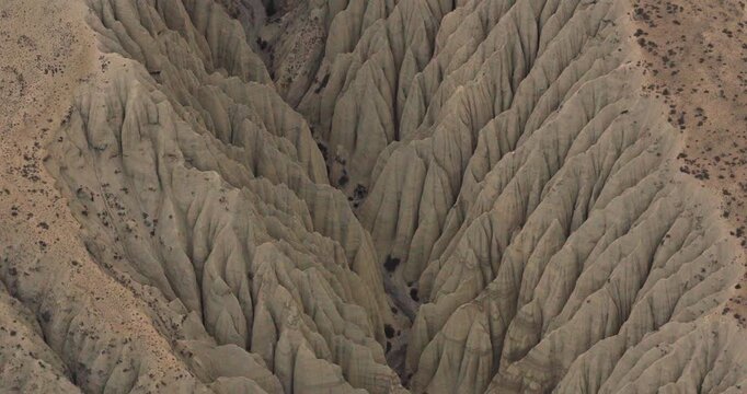 Drone glides smoothly over an insane, deeply furrowed clay mountain canyon, revealing patterns of natural erosion and hill formation in the valleys of Mustang, Nepal